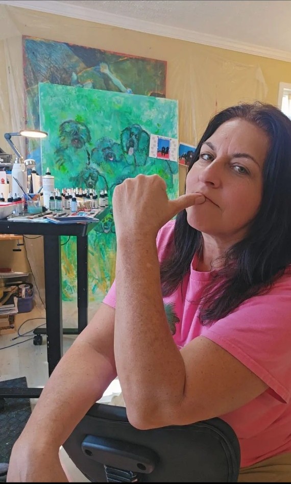 Jennifer in her studio, with colorful paintings around her